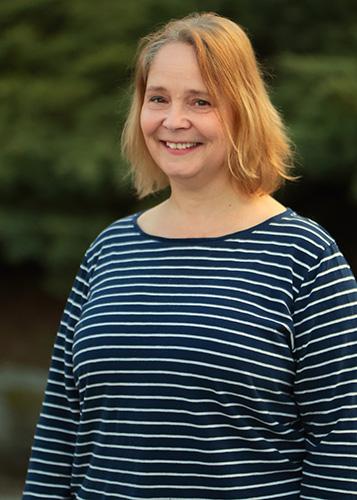 A smiling woman in a blue striped sweater